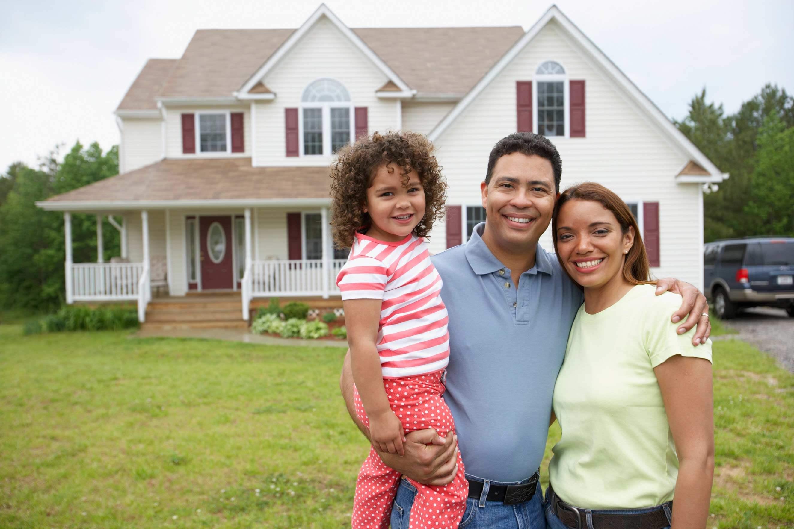 Family of three standing in front of a single family home