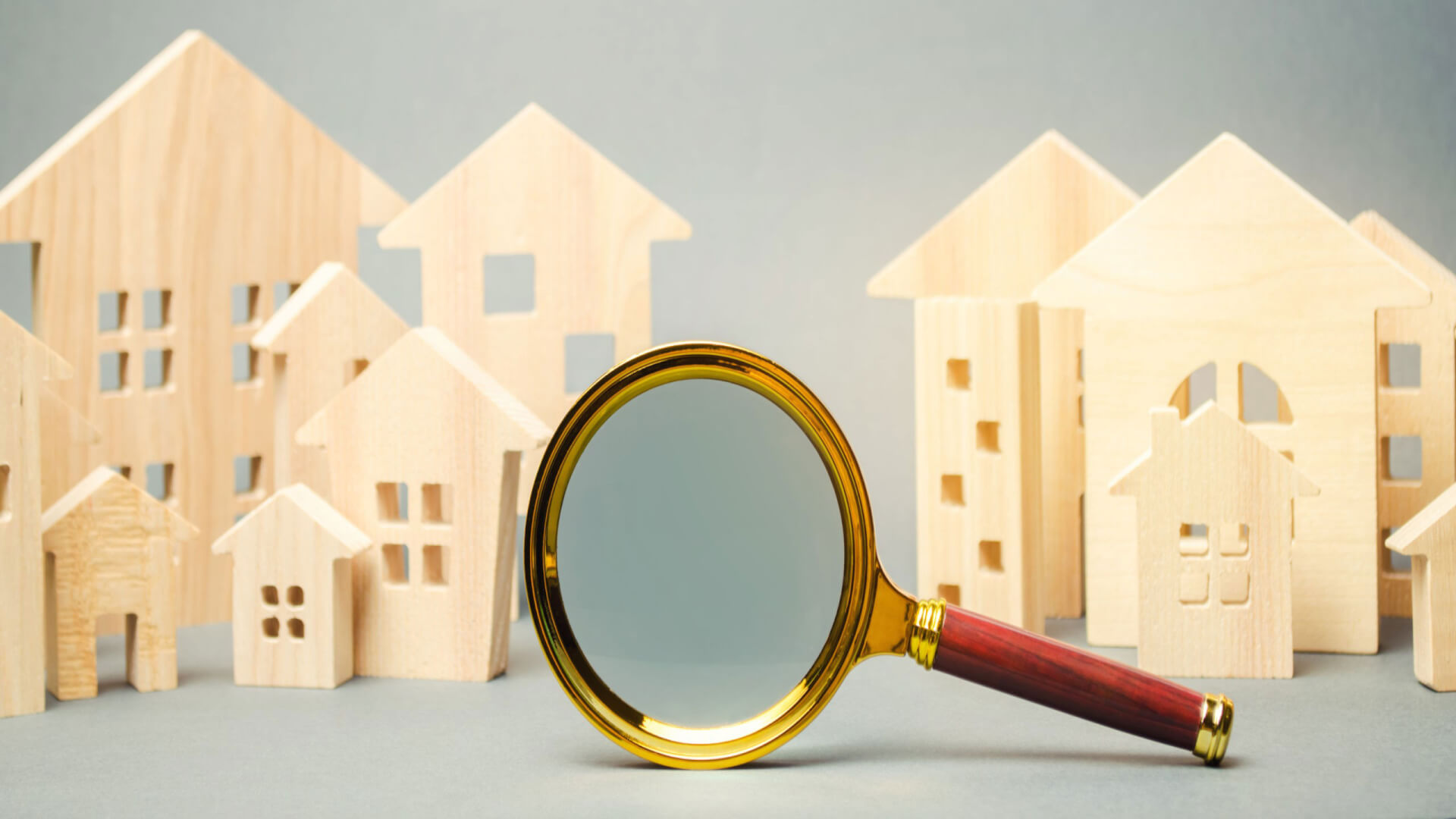 Magnifying glass in front of wooden cut outs of homes