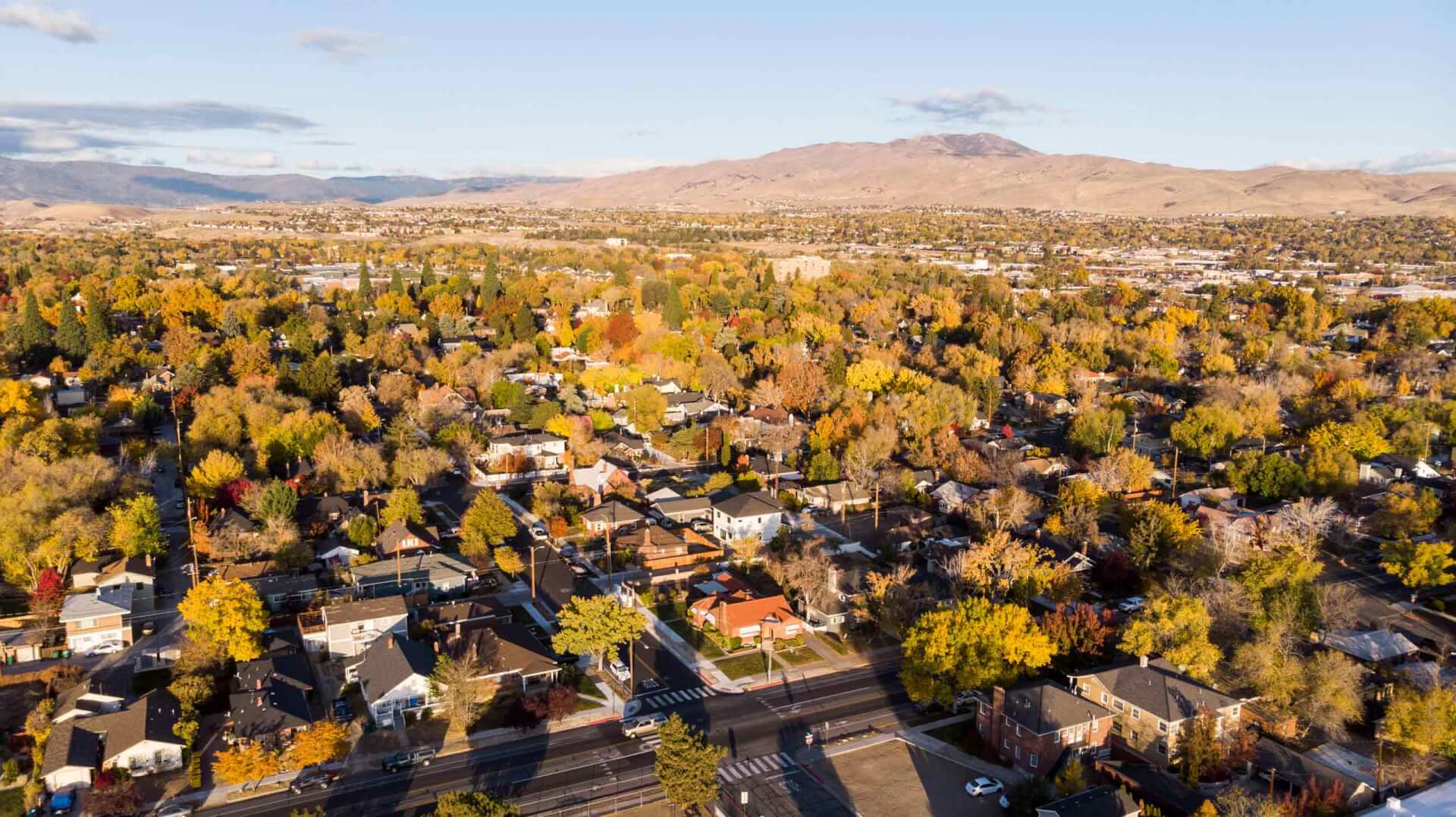 Drone photo of neighborhoods during the fall season looking towards the mountains.