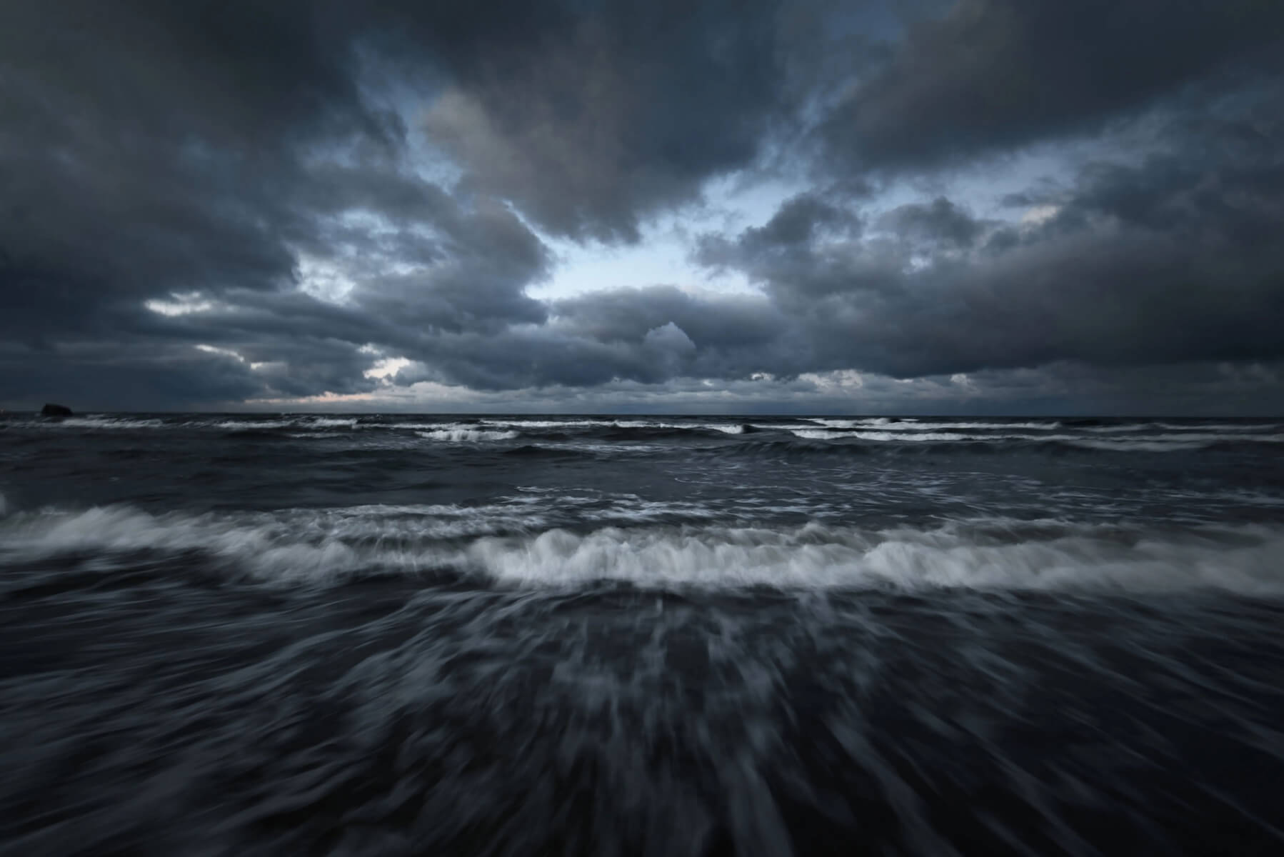 Storm clouds above the Baltic sea in winter, long exposure. Dramatic sky, waves and water splashes. Dark seascape. Germany